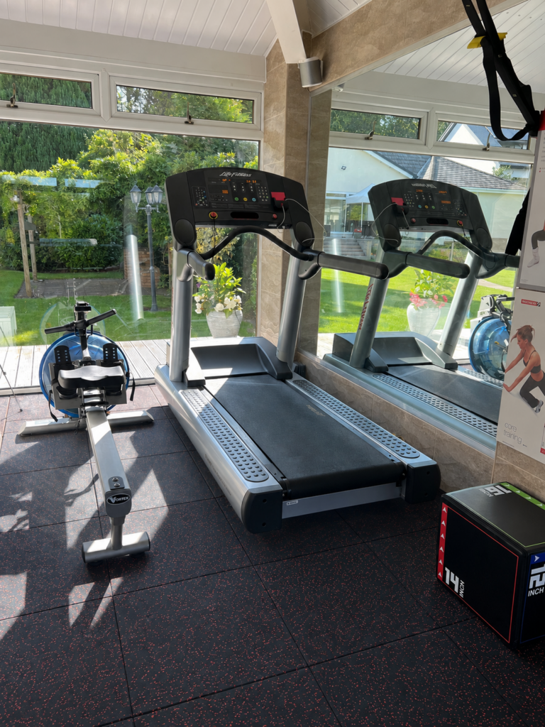 garage gym with eco-tek's multi-flex tiles in black with red specks. Treadmill and rower also in the room